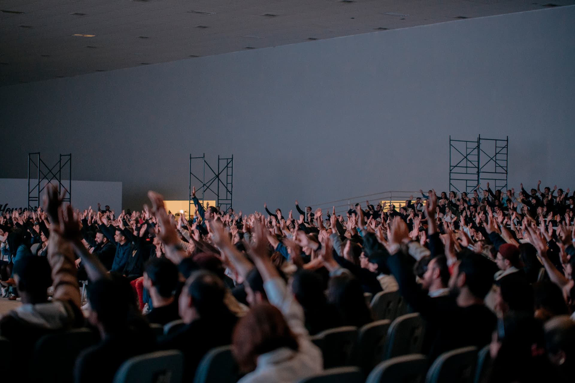 Multidão com as mãos levantadas em adoração no auditório da Celeiro.