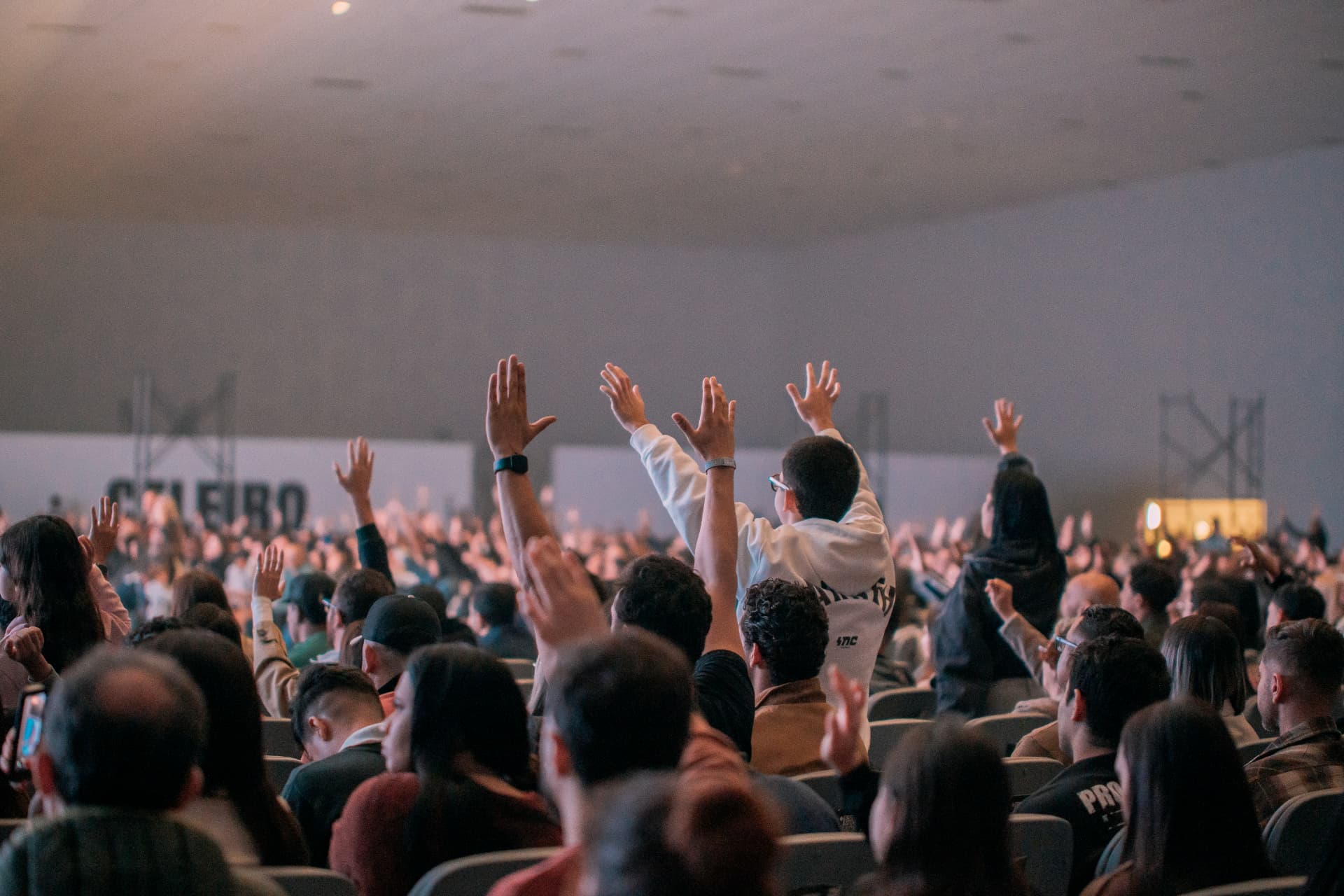 Comunidade da Celeiro reunida com as mãos levantadas durante um culto.